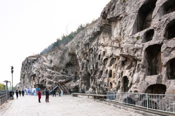 LUOYANG, CHINA - MARCH 20, 2017: people near caves in slope of West Hill of Chinese Buddhist monument Longmen Grottoes. The complex was inscribed upon the UNESCO World Heritage List in 2000