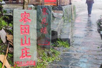 TIANTOUZHAI, CHINA - MARCH 23, 2017: Advertising signs on street in Tiantouzhai village of Dazhai Longsheng country in rain. This is village in famous scenic area of Longji Rice Terraces in China