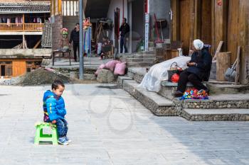 CHENGYANG, CHINA - MARCH 27, 2017: kid and gift seller on square of Folk Custom Centre of Chengyang village of Sanjiang County in spring. Chengyang includes eight villages of Dong people