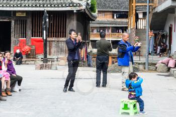 CHENGYANG, CHINA - MARCH 27, 2017: tourists take photos of Dong Culture Show on square of Folk Custom Centre in Chengyang village of Sanjiang County. Chengyang includes eight villages of Dong people