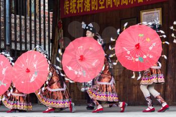 CHENGYANG, CHINA - MARCH 27, 2017: folk dancers with umbrellas in Dong Culture Show in Folk Centre of Chengyang village of Sanjiang County in spring. Chengyang includes eight villages of Dong people
