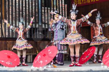 CHENGYANG, CHINA - MARCH 27, 2017: folk players with umbrellas in Dong Culture Show in Folk Centre of Chengyang village of Sanjiang County in spring. Chengyang includes eight villages of Dong people