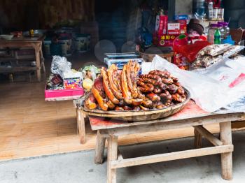 CHENGYANG, CHINA - MARCH 27, 2017: local smoked pork products in front of eatery in Chengyang village of Sanjiang Dong Autonomous County in spring. Chengyang includes eight villages of the Dong people