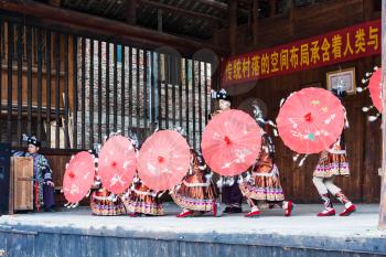 CHENGYANG, CHINA - MARCH 27, 2017: dancers with umbrellas in Dong Culture Show in Folk Centre of Chengyang village of Sanjiang County in spring. Chengyang includes eight villages of Dong people