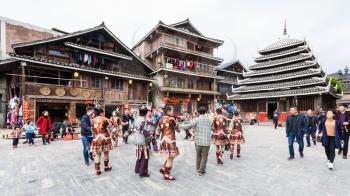 CHENGYANG, CHINA - MARCH 27, 2017: tourists and round dance on square of Folk Custom Centre during Dong Culture Show in Chengyang village in spring. Chengyang includes eight villages of Dong people