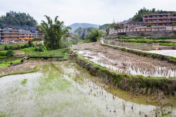 CHENGYANG, CHINA - MARCH 27, 2017: people near terraced rice fields in Chengyang village of Sanjiang Dong Autonomous County in spring. Chengyang includes eight villages of the Dong people