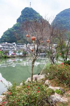 YANGSHUO, CHINA - MARCH 30, 2017: tree with lanterns on waterfront in Yangshuo city in spring. Town is resort destination for domestic and foreign tourists because of scenic karst peaks