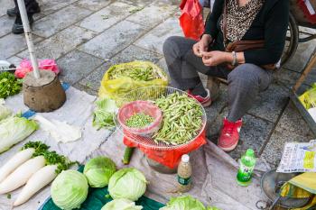 YANGSHUO, CHINA - MARCH 30, 2017: seller of beans on street outdoor market in Yangshuo city in spring. Town is resort destination for domestic and foreign tourists because of scenic karst peaks