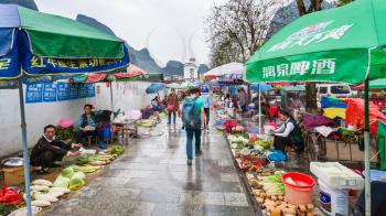 YANGSHUO, CHINA - MARCH 30, 2017: people on street outdoor vegetable market in Yangshuo in spring. Town is resort destination for domestic and foreign tourists because of scenic karst peaks
