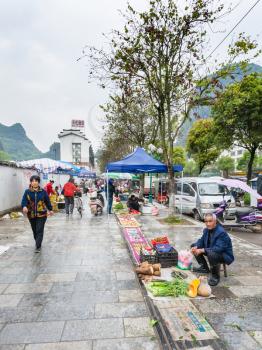 YANGSHUO, CHINA - MARCH 30, 2017: people on garden vegetable market on street in Yangshuo in spring. Town is resort destination for domestic and foreign tourists because of scenic karst peaks