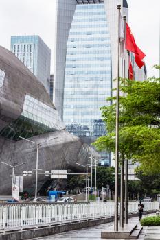 GUANGZHOU, CHINA - MARCH 31, 2017: skyscrapers and Opera House and flags in Zhujiang New Town of Guangzhou city in overcast day. Theater was designed by Zaha Hadid, and opened in 2010.