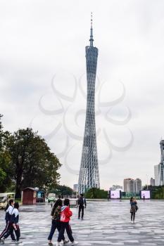 GUANGZHOU, CHINA - MARCH 31, 2017: people on square in Zhujiang New Town of Guangzhou city in rainy day and Guangzhou (Canton) TV Astronomical and Sightseeing Tower. The tower was topped out in 2009