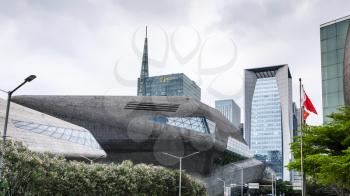 GUANGZHOU, CHINA - MARCH 31, 2017: Opera House and flag in Zhujiang New Town of Guangzhou city in spring rain. Theater was designed by Zaha Hadid, and opened in 2010.