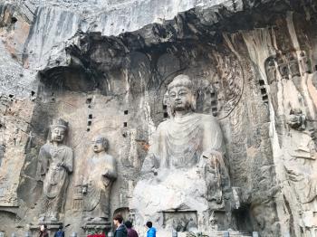 LUOYANG, CHINA - MARCH 20, 2017: people near The Big Vairocana statue in main Longmen Grottoes (Longmen Caves). The complex was inscribed upon the UNESCO World Heritage List in 2000