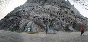 LUOYANG, CHINA - MARCH 20, 2017: tourist and panorama of West Hill with caves in Chinese Buddhist monument Longmen Grottoes. The complex was inscribed upon the UNESCO World Heritage List in 2000