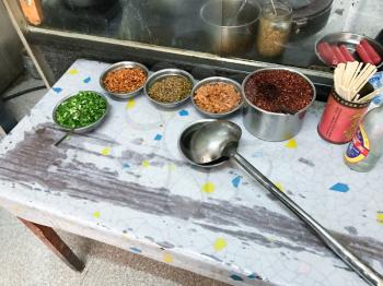 LONGSHENG, CHINA - MARCH 25, 2017: Seasonings, spices and toppings on kitchen table in urban eatery in Longsheng town. Longsheng is a small city in the south central Chinese province of Guangxi