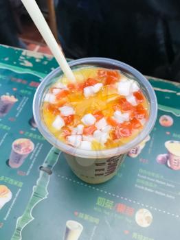 YANGSHUO, CHINA - MARCH 27, 2017: Chinese fruit drink from Juice and pieces of peach, mango, coconut in cafe of Yangshuo city. Freshly squeezed juices from exotic fruits are very popular in China