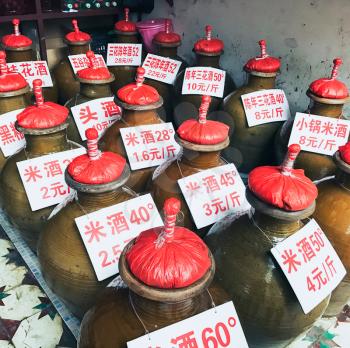 YANGSHUO, CHINA - MARCH 28, 2017: jugs with home-made alcohol drinks on local market in Yangshuo town. Baijiu is Chinese alcoholic beverage from strong distilled spirit, generally between 40 and 60%