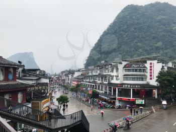 YANGSHUO, CHINA - MARCH 28, 2017: people on shopping West Street in Yangshuo city in rainy spring evening. Town is resort destination for domestic and foreign tourists because of scenic karst peaks