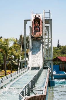 girls in boat on water slide attraction in summer day