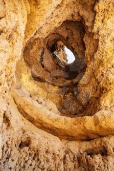 Travel to Algarve Portugal - hole in eroded sandstone rock on beach Praia Maria Luisa near Albufeira city in sunny day