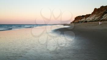 Travel to Algarve Portugal - tourists walk on beach Praia Falesia near Albufeira city during evening ebb