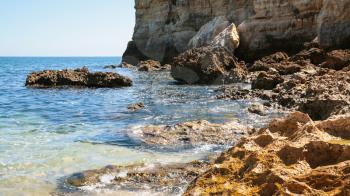 Travel to Algarve Portugal - coquina rocks on coastline of beach Praia Maria Luisa near Albufeira city in sunny day