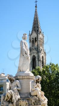 Travel to Provence, France - statue of Pradier fountain and view of tower Church Sainte Perpetue et Sainte Felicite de Nimes in Nimes city