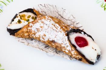 typical sicilian pastry Cannoli sprinkled with confectioner's sugar omn white plate