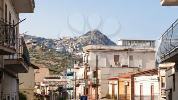 travel to Sicily, Italy - apartment houses on street via Vittorio Emanuele in Giardini Naxos town and view of Taormina city on mountaan in summer