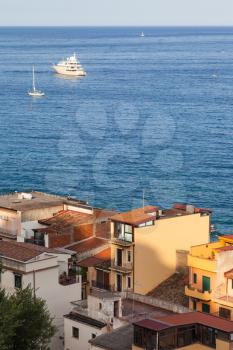 travel to Sicily, Italy - above view of residential houses in Giardini Naxos town and ships in Ionian Sea at summer sunset