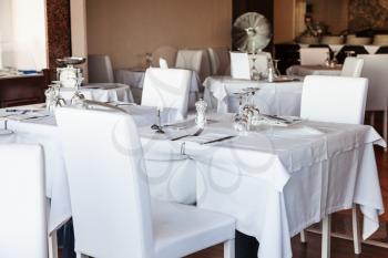 white leather chairs and tables covered with white tableclothes in sicilian restaurant