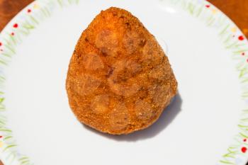 traditional sicilian street food - one meat stuffed rice ball arancini on table
