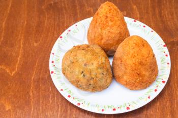 traditional sicilian street food - various rice balls arancini on plate on table