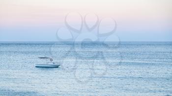 travel to Sicily, Italy - one boat on blue water of Ionian sea near Giardini Naxos town in blue summer evening