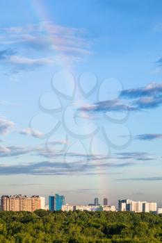 rainbow in blue evening sky over apartment houses and Timiryazevsky park in Moscow city in summer