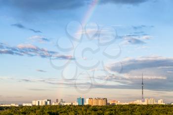 rainbow in blue evening sky over residential district with Ostankino TV tower and Timiryazevsky park in Moscow city in summer