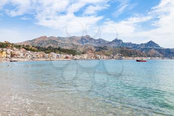 travel to Sicily, Italy - water of Ionian sea near waterfront of Giardini Naxos town and view of Taormina city on cape in summer