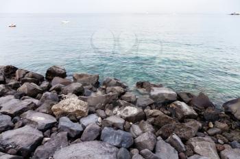 travel to Sicily, Italy - volcanic rocks on waterfront of Giardini Naxos town in summer
