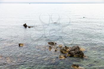 travel to Sicily, Italy - rocks in water near waterfront in Giardini Naxos town in summer