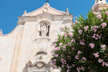 travel to Sicily, Italy - oleander tree and facade of church Chiesa di San Giuseppe at Piazza IX Aprile in Taormina city in summer day