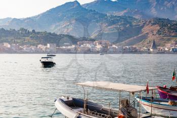 travel to Sicily, Italy - boats in Ionian Sea and view of Giardini Naxos town from port in summer evening