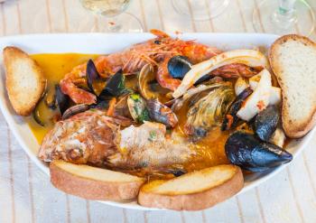 typical italian food - fish soup with seafood in sicilian restaurant