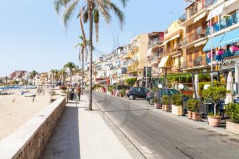 GIARDINI NAXOS, ITALY - JUNE 29, 2017: people on waterfront and beach in Giardini-Naxos town in summer. Giardini Naxos is seaside resort on Ionian Sea coast since the 1970s