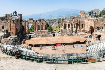 TAORMINA, ITALY - JUNE 29, 2017: tourists in Teatro antico di Taormina, ancient Greek Theater (Teatro Greco) and view of Etna mount in summer day. The amphitheater was built in the third century BC