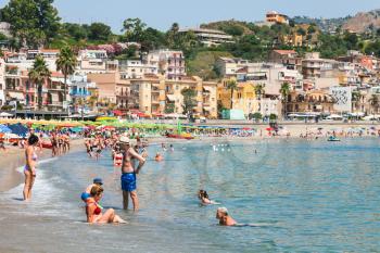 GIARDINI NAXOS, ITALY - JUNE 30, 2017: tourists on urban beach in Giardini-Naxos city in summer. Giardini Naxos is seaside resort on Ionian Sea coast since the 1970s