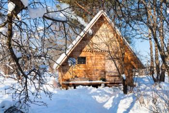 new little wooden cottage in snow-covered garden in sunny winter day in Smolensk region of Russia