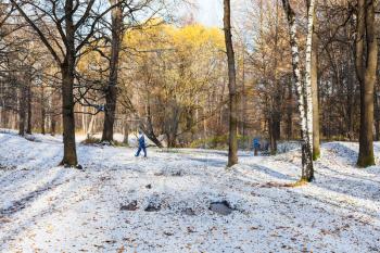 view of city park covered with the first snow in sunny autumn day