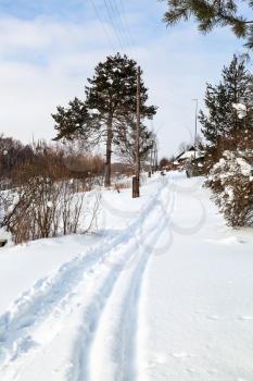 footpath and ski run along little russian village in winter day in Smolensk region of Russia