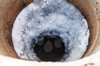 top view of frozen water and ice hole in well in cold winter day